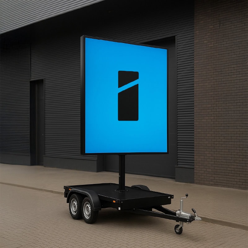 Groot blauw mobiel LED reclamebord met Smid Media Solutions logo op aanhangwagen voor industrieel gebouw