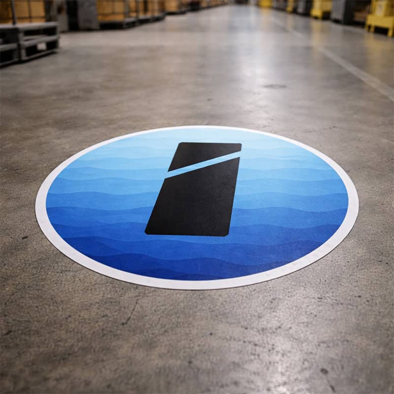 Ronde blauwe vloersticker met golfpatroon en Smid Media Solutions logo op betonnen magazijnvloer